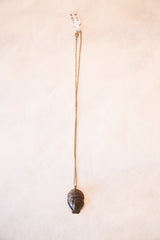 African head pendant necklace with dark bronze patina hanging from its full-length chain.
