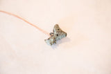Angled view of the vintage rooster pendant showing its textured, oxidized blue-green patina.