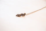 Angled view of the handmade lizard pendant with its curled tail and thin chain.