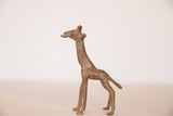 Side profile of a small vintage bronze giraffe figurine showing its textured, time-worn patina.