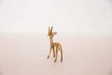 A small golden bronze gazelle fawn figurine turning its head to look back.