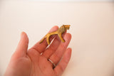 Vintage African golden bronze lion sculpture held in hand, showing its textured surface and small scale.