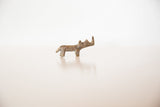Profile view of a miniature bronze rhino highlighting its handmade texture and aged patina.