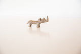 The stylized shape and greenish bronze patina of a miniature African rhino figurine.