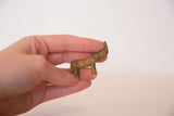 Miniature vintage African bronze rhinoceros with sloped back, held in hand.