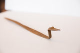 Textured, bent form of the vintage African iron snake sculpture, showing its patina.