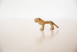 Profile view of a small collectible bronze lion with a textured, rusty patina.