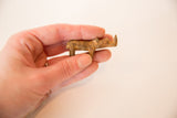 Side view of the small vintage bronze rhino, showing its simple handmade form and patina.
