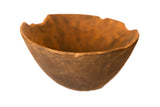 A hand-carved vintage African wooden bowl with a rustic, weathered patina and an irregular rim.