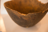 The rustic, hand-carved texture and aged imperfections of the vintage bowl's rim.
