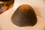 The dark, textured exterior of a hand-carved African bowl showing aged character and repairs.