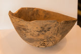 Vintage African wooden bowl's weathered edge and visible cracks, showing primitive hand-carved texture.