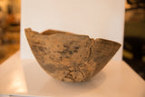 Chipped rim and prominent cracks on a vintage African wooden bowl.