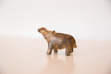 Side profile of the vintage bronze hippo with its head raised, showing a mottled rust patina.
