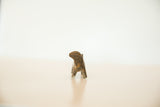 The turning posture of a handmade African bronze hippo seen from behind.