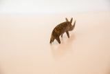 Vintage skinny bronze rhino figurine shown from a soft-focus, angled rear perspective.