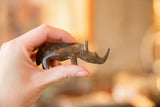Vintage African bronze rhino figurine held in hand to show its small scale and texture.