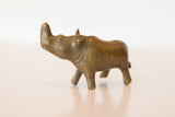 Profile view of a vintage bronze rhino figurine, showing its aged patina and turning posture.