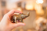 Vintage African bronze rhino figurine held in hand to demonstrate its scale.