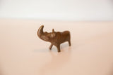Profile view of a vintage cast copper rhino showing its handmade, aged surface.