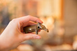 The handmade bronze hippo sculpture held in a hand to illustrate its size.