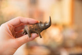 Vintage dark copper rhinoceros sculpture with aged patina, held in hand.
