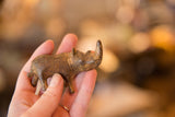 Aged bronze rhinoceros sculpture held in hand, emphasizing its unique handmade texture.
