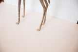 Weathered patina on the slender legs and feet of the bronze giraffe sculpture.