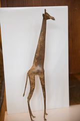 Side profile of a vintage bronze giraffe highlighting its stylized shape and textured, oxidized finish.