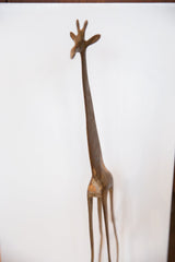 Low-angle view of the tall bronze giraffe sculpture, highlighting its slender neck and patina.