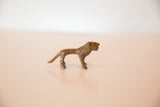 The stylized form and aged patina of a vintage mini copper lion in profile.