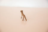 A view from behind the vintage mini copper lion, showing its handmade form and slender legs.
