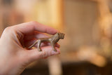 Side profile of a miniature cast copper lion showing its handmade, textured finish.