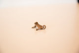 Arched profile of a vintage cast copper frog charm with a warm patina.