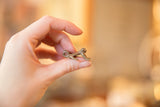 Vintage copper frog pendant held in hand to demonstrate its delicate, small scale.