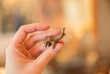Handmade vintage copper elephant held between fingers to show its miniature scale.