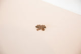 Overhead view of a vintage African copper turtle pendant showing its textured cast body.
