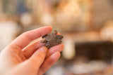 Vintage African copper turtle pendant held between fingers to show scale.