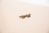 The textured surface and aged patina of the vintage copper lizard pendant.