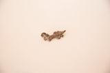 Side profile of a cast copper lizard charm highlighting its intricate texture.