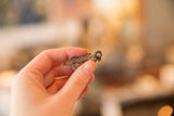 Vintage copper lizard pendant held in a hand to show its small scale and texture.