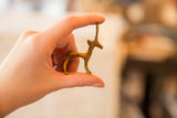 A hand holding the small bronze gazelle figurine to show its miniature scale.