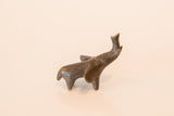 Small vintage bronze elephant figurine seen in profile, with its trunk lifted.