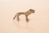 Side profile of a small vintage bronze lion showing its handmade form and dusty patina.
