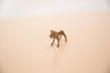 High-angle side view of a vintage bronze mini lion showing its simple form and dusty patina.