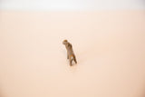 The abstract, hand-cast form of a tiny bronze hippo, seen from behind.
