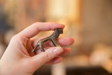 Miniature African lion figurine with dark gold patina, held in hand.