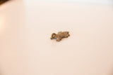 Angled view of a small bronze turtle pendant showing its rustic cast texture.