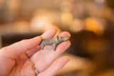 A vintage mini bronze hippo held in hand, showing its dusty patina.