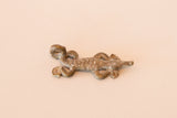 Angled view of a vintage bronze lizard pendant showing its textured back and dusty patina.